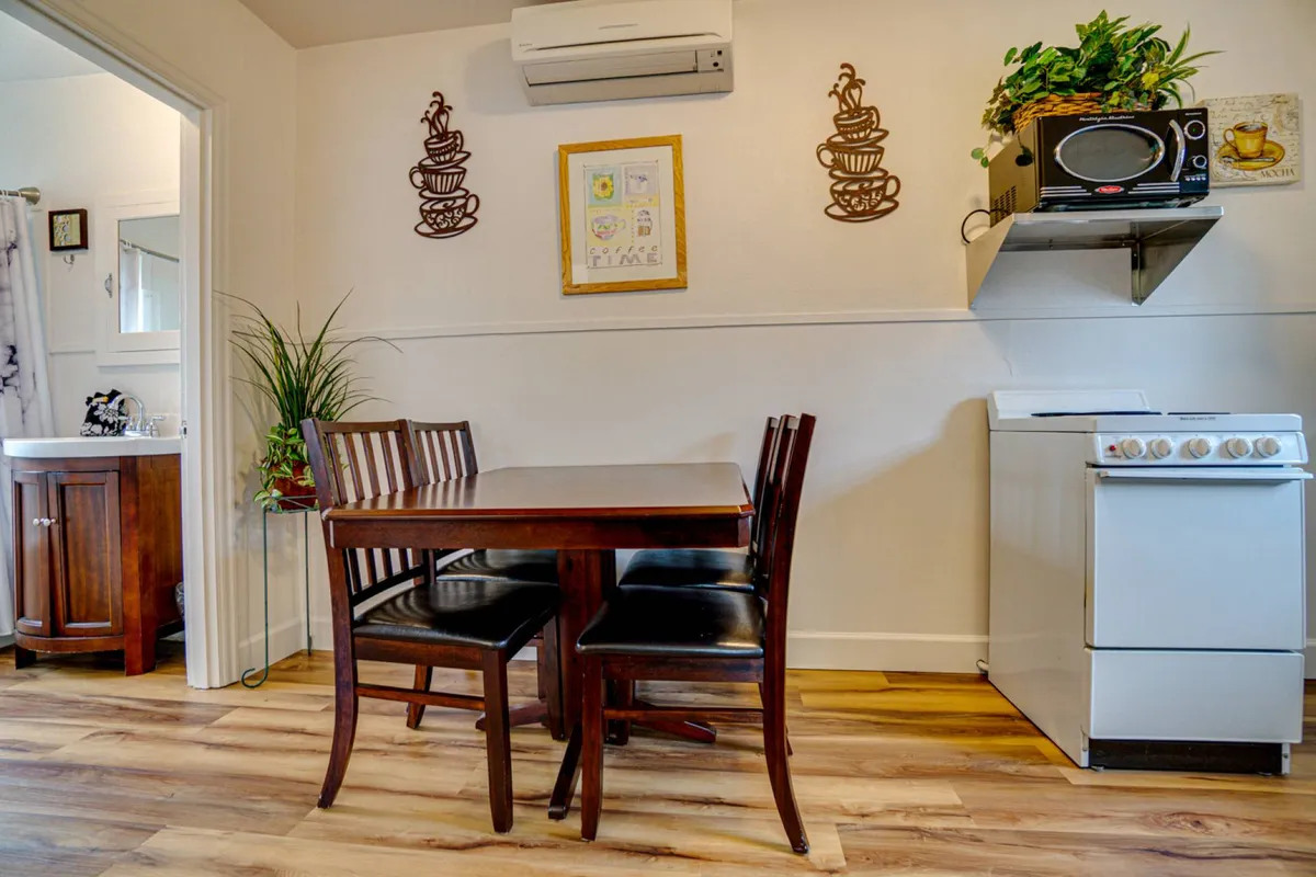 This image features a warm, welcoming kitchen and dining area with a wooden dining table, black leather chairs, and visible kitchen appliances. Decorative wall art adds a touch of personality. The scene feels inviting and is ideal for both dining and socializing, reflecting the multifunctionality described in the section.